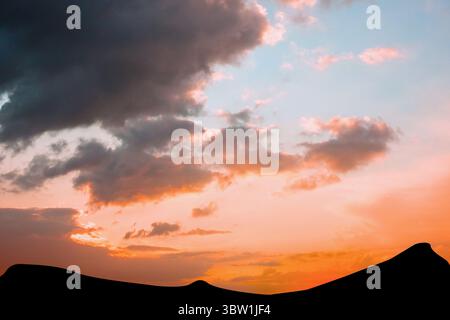 Flat design illustration showing rolling desert sand dune silhouettes under glowing sunset clouds Stock Photo