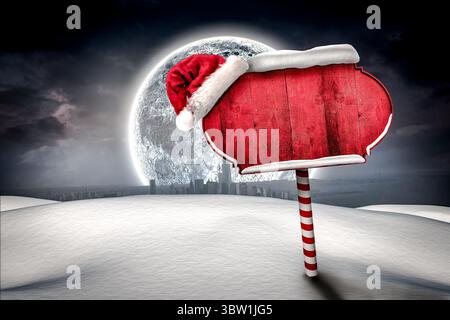 Showing red signboard trimmed topped by Santa hat on striped pole against moonlit snowy skyline Stock Photo