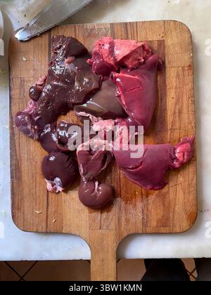 Chicken offal, liver, heart, kidneys, and gizzards, lying on a wooden cutting board, ready for cooking, healthy food, high in iron and vitamins, tradi Stock Photo