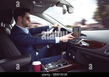 Man is gripping steering wheel while touching dashboard touchscreen in flat design, with coffee cup Stock Photo