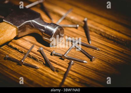 Flat design showing metallic hammer head with wooden handle resting on plank, featuring steel nails Stock Photo