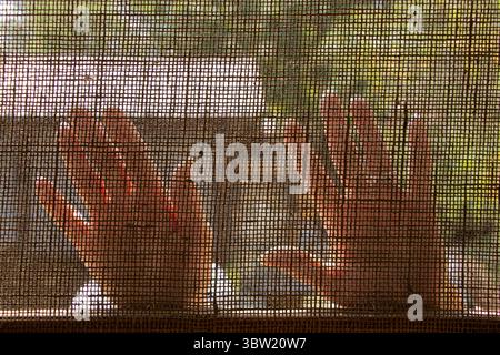 Women's hands pressed against light fabric with mesh texture in the light, palms through fabric on the street Stock Photo