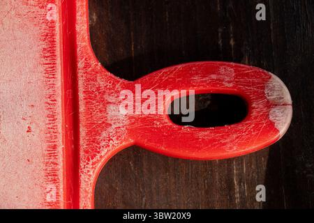 Red plastic kitchen cutting board and handle with scratches and cuts as background close-up Stock Photo