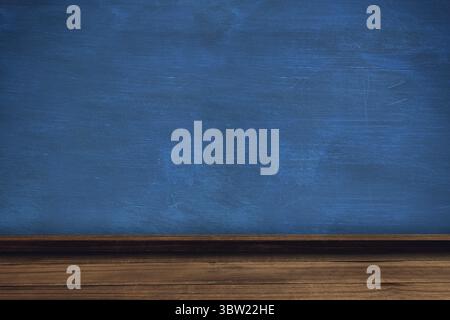 Blue chalkboard is sitting above wooden ledge and desk in classroom showing chalk smudges Stock Photo