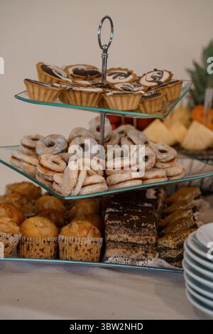 An inviting overhead shot captures a tiered glass dessert stand filled with an assortment of treats like mini pies, cookies, and brownies, ideal for p Stock Photo