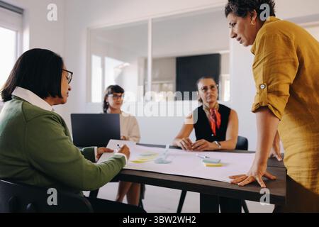 A team of professionals engaged in a brainstorming meeting discussion in a modern workspace. They use notes and tools to collaborate and share ideas e Stock Photo