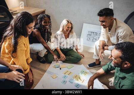 A group of diverse male and female architects discuss and brainstorm ideas for a project, demonstrating teamwork and collaboration in a modern workspa Stock Photo