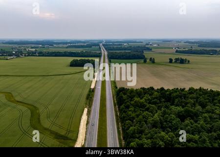 Lonely road cutting through vast field. Stock Photo