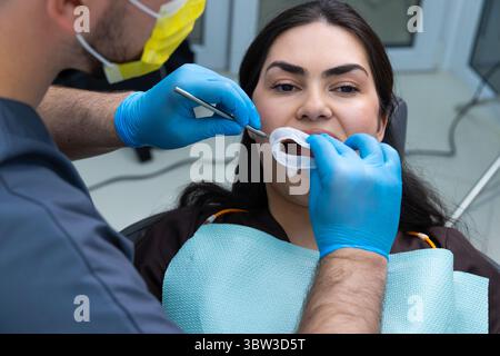 A Dentist Performing an Oral Examination with Precision and Care, Ensuring Patient Comfort with a Clean and Welcoming Environment Focused on Dental Stock Photo