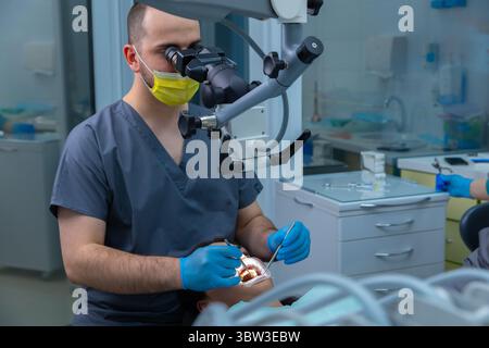 Professional dentist performing a dental procedure with surgical microscope, ensuring precision and care during patient treatment in a modern dental Stock Photo
