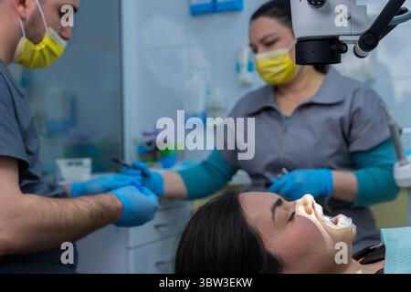 A Dental Procedure in Progress with Two Practitioners: One Focused on Patient Care and the Other Preparing Instruments for a Successful Check-up Stock Photo