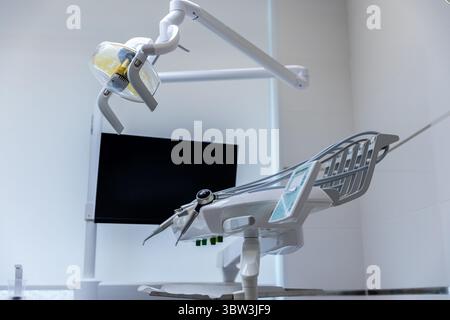 Modern Dental Treatment Room Featuring Advanced Equipment Including a Dental Chair, Overhead Light and Monitor for Patient Care and Comfort During Stock Photo