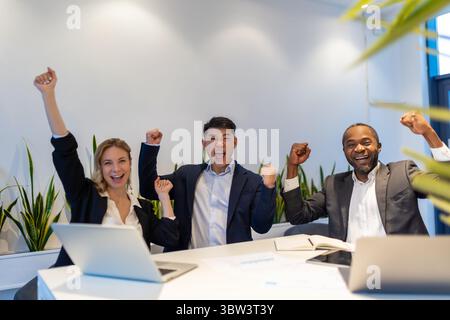 Multiethnic business team sitting at desk collaborating on project with laptop and documents Stock Photo