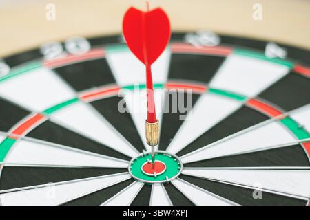 Dart arrow hitting in the target center of dartboard Stock Photo