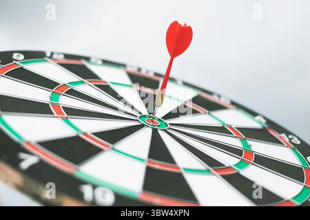 Dart arrow hitting in the target center of dartboard Stock Photo