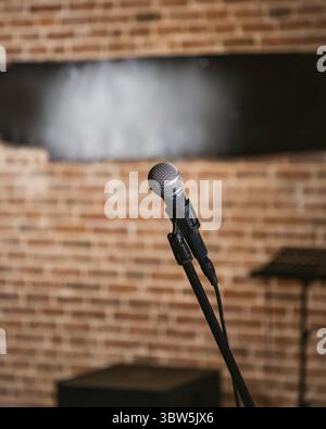 Microphone is standing on stage, ready for a performance, with a brick wall in the background Stock Photo