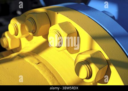 Two blue and yellow gas pipes are connected by large bolts and nuts. Background for suppliers of gas products and pipes. Close-up Stock Photo
