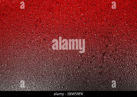 Red surface with drops of water or liquid with a gradient transition to a dark color. Abstract background on the theme of high temperature and heat Stock Photo