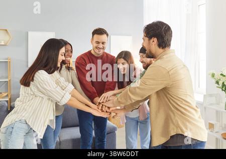 Cheerful friends group meeting, multiethnic team of young people giving common high five Stock Photo