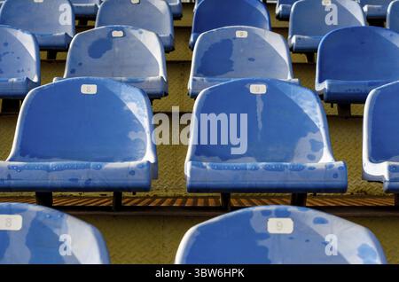 Rows of identical wet blue seats in the empty stadium bleachers Stock Photo