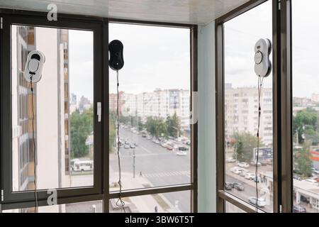 Three automatic window cleaning robots washing windows of modern apartment building, providing efficient and convenient cleaning solution for high Stock Photo