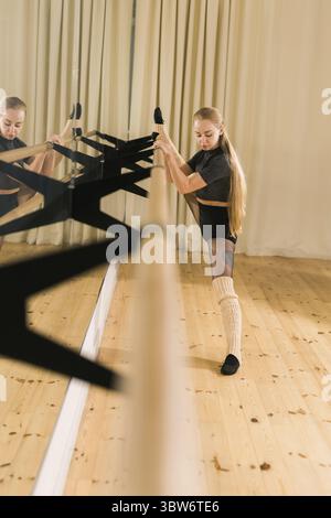 Female ballet dancer practicing at barre in dance studio - dance and ballerina Stock Photo