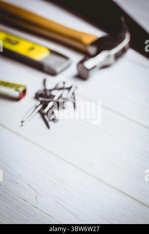 Flat illustration is showing claw hammer lying on white plank with nails and tools, copy space Stock Photo