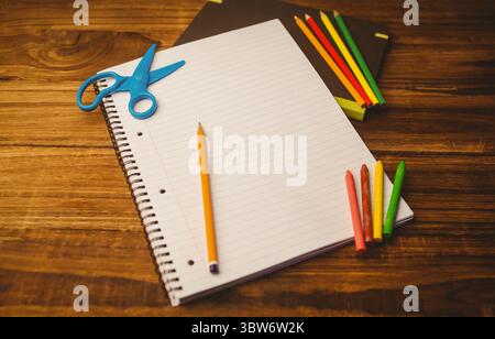 Spiral-bound notebook is lying on desk in flat design with pencil, scissors and colorful art tools Stock Photo
