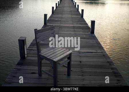 An old woodeng chair on a wooden bridge over an artificial lake in Semarang, Central Java, Indonesia. Stock Photo
