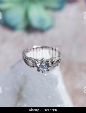 Silver ring with big diamond sparkling on white stone is perfect as a gift for valentine's day or wedding Stock Photo