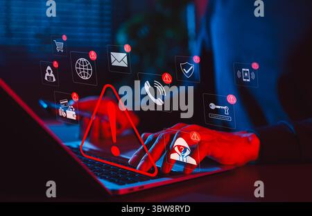 Online scam alert and cybersecurity warning concept. Man holding phone while using laptop, warning sign for scam with icons online threats, phishing, Stock Photo