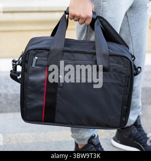 Young man holding a black sport bag close up Stock Photo