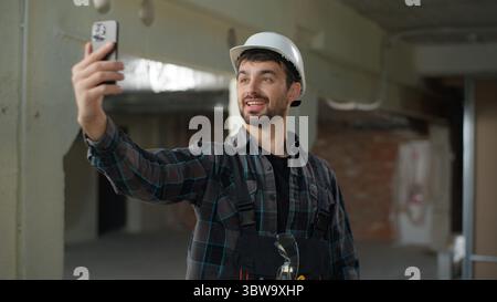 Construction engineer man builder Caucasian guy male talk video call mobile phone conference chat on building site handyman foreman architect talking Stock Photo