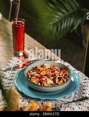 Bowl of fresh and healthy coleslaw salad with cabbage, oranges, pomegranate seeds and dressing on a table Stock Photo