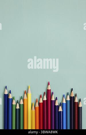 Colored sharpened pencils lie on a blue background with space for copying. School supplies or school preparation. Top view Stock Photo