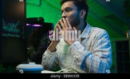 Worried Indian Arabian man guy streamer programmer hacker computer hope cross fingers loss failure error lost crypto freelancer crash studio home Stock Photo