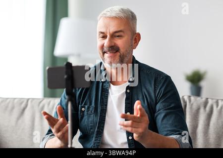 Smiling senior man vlogger broadcasting from home Stock Photo