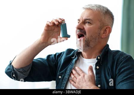 Senior man touching chest and using inhaler Stock Photo