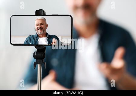 Mobile phone screen with cheerful senior man blogger Stock Photo