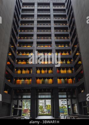 Modern apartment building in Japan with colorful balconies at night. Geometric architecture, illuminated rooms, and a tranquil courtyard create a stri Stock Photo