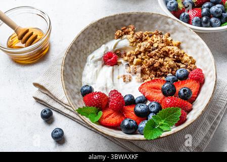 Granola bowl for healthy fitness breakfast. Homemade granola with greek yogurt, fresh berries and honey close up. Healthy eating concept. Stock Photo