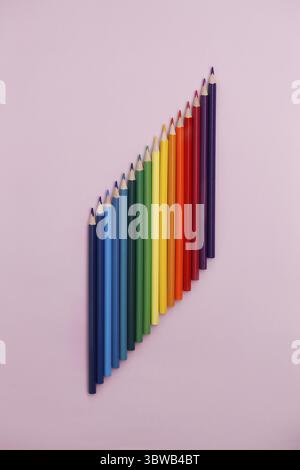 Colored pointed pencils lie on a pink background with space for copying. School supplies or school preparation. Top view Stock Photo