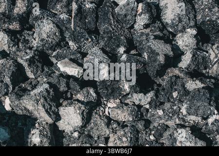 Repair of the road surface. A pile of stones made of old asphalt lies on the road. Textured abstract background. Close-up Stock Photo