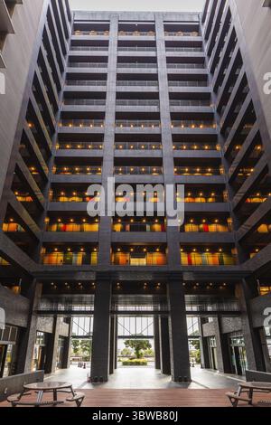 Modern building interior courtyard with multiple floors of balconies and lights. A minimalist architectural design with dark exteriors and colorful ac Stock Photo