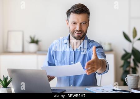 Job Interview. Friendly male HR manager extending hand for handshake at camera Stock Photo
