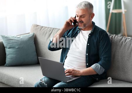 Matured man entrepreneur working online, using laptop and mobile phone Stock Photo