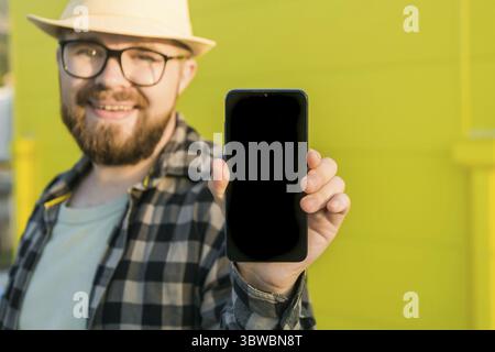 Hot offering. Happy guy holds cellphone with black copy space and smiling. Human emotions facial and place for advertising and text Stock Photo