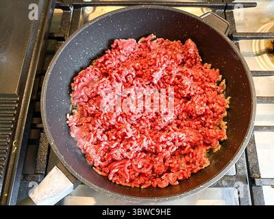 Close up view of a large pan of mince beef on the hob of a cooker. Home cooking concept. Stock Photo