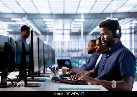 Engineer hearing podcasts to make time pass faster while working in server farm to optimize it for data processing requirements. IT expert listens songs and ensures data center operates efficiently Stock Photo