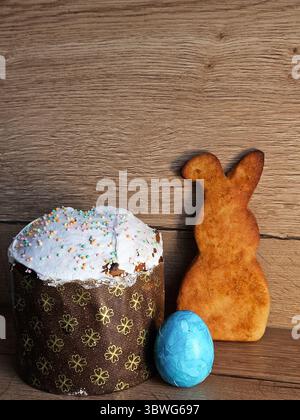 Festive Easter scene featuring a decorated cake, a bunny-shaped cookie, and a blue painted egg on a rustic wooden surface, symbolizing traditional Stock Photo